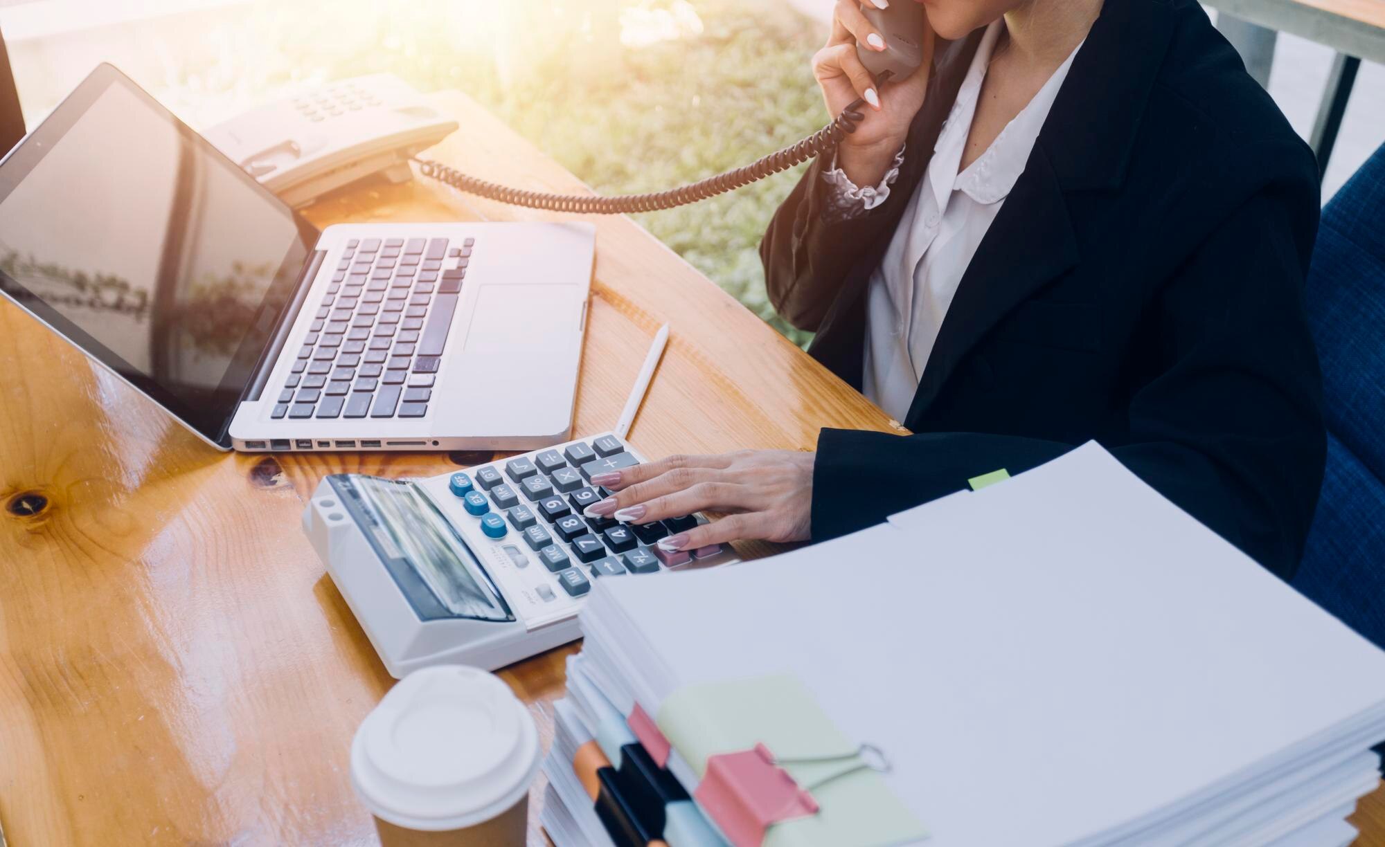Bookkeeper working with calculator and financial documents at a desk